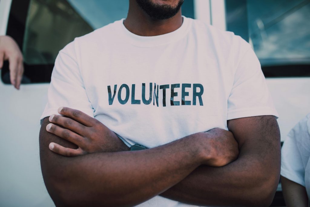 pexels photo 6646852 6646852 A close-up of a person wearing a volunteer shirt with arms crossed, promoting community service.