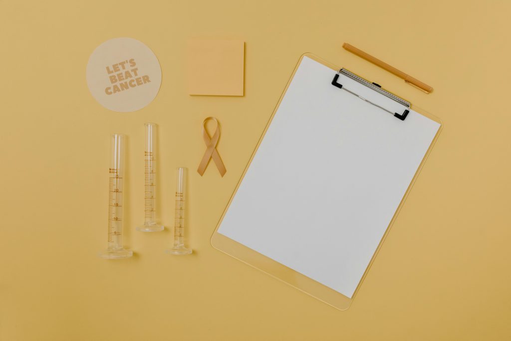 pexels photo 7723559 7723559 Flat lay of medical tools and cancer awareness ribbon on yellow background.